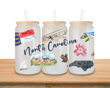 Load image into Gallery viewer, North Carolina frosted glass can tumbler with bamboo lid and glass straw featuring a wraparound watercolor design of state icons and landmarks.
